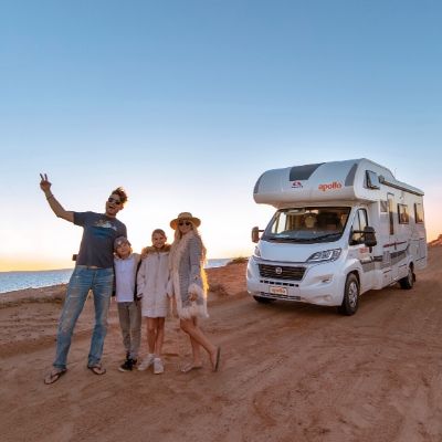 Family standing in front of Apollo Motorhome on beach